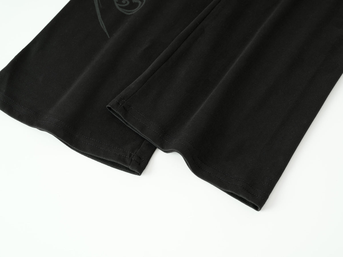 Close-up of a black fabric garment, likely a shirt or shorts, folded to show the texture and hem on a white background.